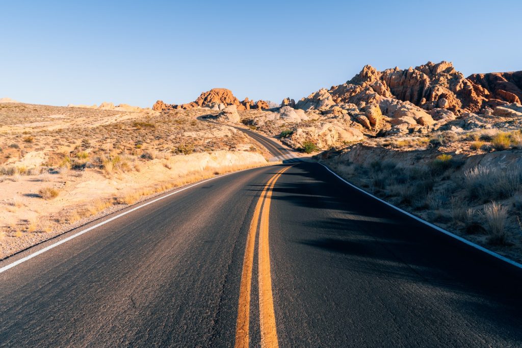 a road in the middle of a desert with mountains in the background